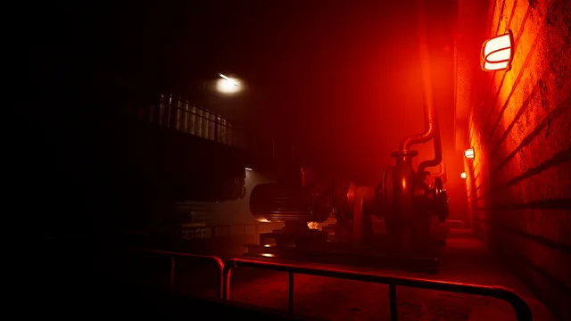 Industrial machinery lit red beside a brick wall in a dark facility
