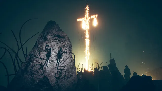 A burning cross in the fog behind a rock carved with human figures, a silhouette standing nearby