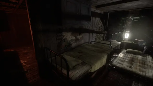 A dark room of iron beds lit by a lamp by the window