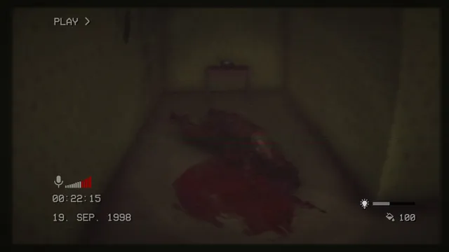 The Backrooms 1998 screenshot: a bloody mass of remains on the floor of a narrow dark corridor in VHS footage