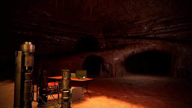 Machinery and a desk with computer screens in a red-lit underground cave