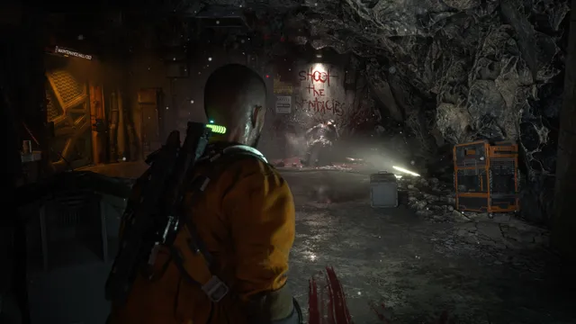 The Callisto Protocol screenshot: Jacob in an orange prison suit faces a dark tunnel where 'shoot the tentacles' is written in blood