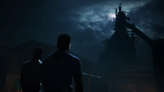 Two young men silhouetted against the dark tower of a steel mill under a cloudy moon