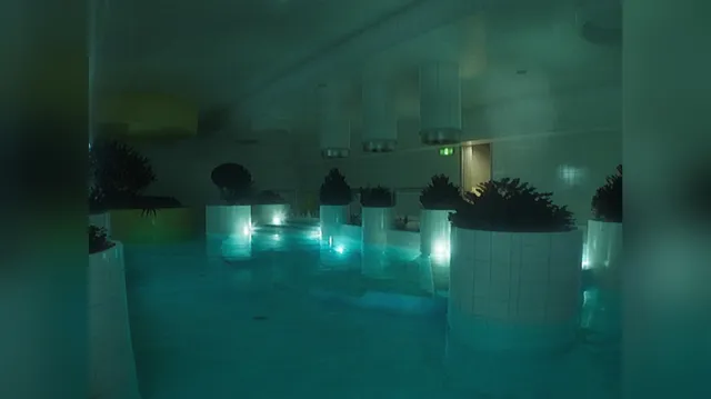 A flooded room of white tiled planters and glowing water