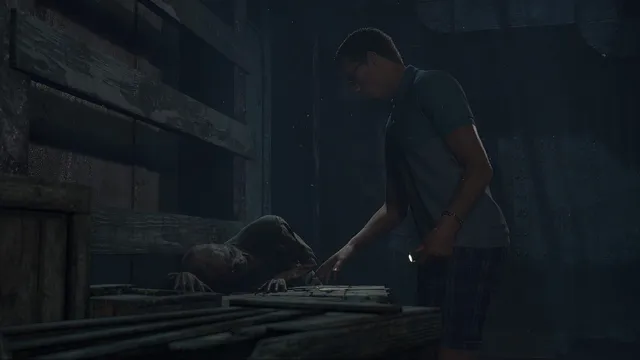 Man of Medan screenshot: Alex holds a torch over a wooden crate as a corpse's hand reaches out beside him