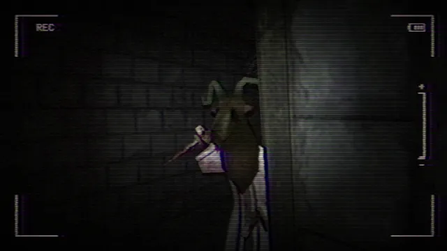The Fear Business screenshot: through a camcorder's REC frame, a goat-masked killer raises a bloody knife around a corner of a stone wall