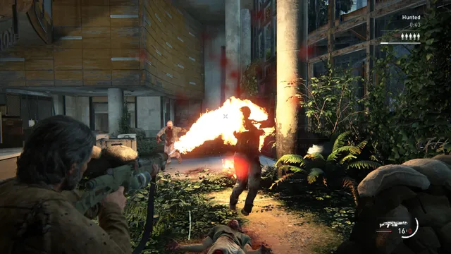 The Last of Us Part II Remastered screenshot: in the No Return mode, a survivor aims a rifle from cover as a flamethrower blast engulfs an attacker in an overgrown ruin