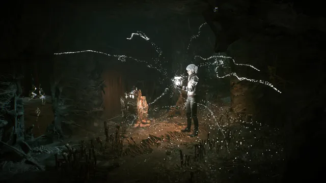 The Medium screenshot: the spirit Marianne in a dark cave, light pouring from her hand as glowing threads spread around a small shrine