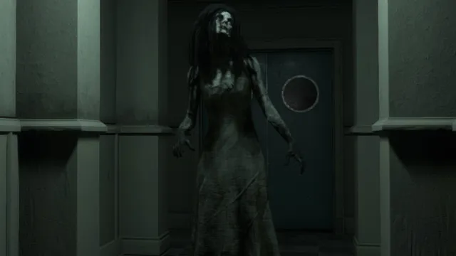 The Mortuary Assistant screenshot: a gaunt woman with long dark hair and a skull-like face reaches out in front of a steel door