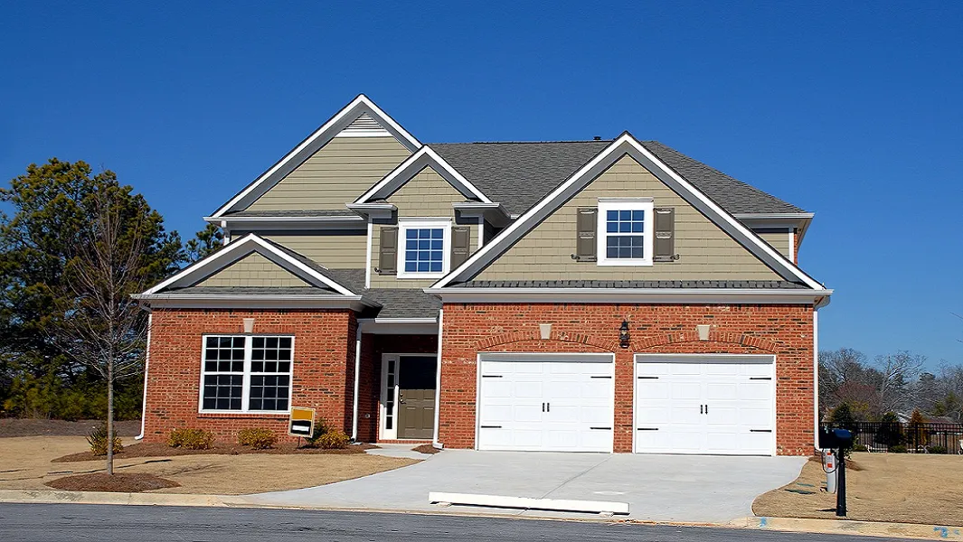 The Open House screenshot: the listing photo of a red-brick two-storey house with a double garage under a blue sky