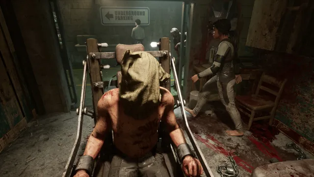 The Outlast Trials screenshot: a hooded, bloodied man strapped to a wooden chair while test subjects move around him in a bloodstained room