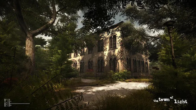 The overgrown grounds and arched brick building of the abandoned asylum on a sunny day