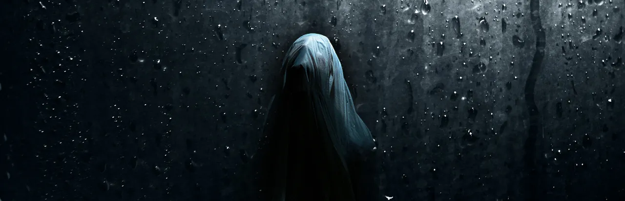 Visage art: a veiled ghostly figure seen through a rain-spattered window in the dark