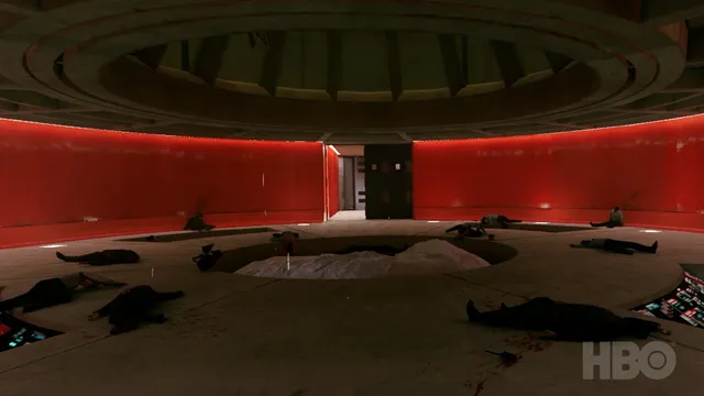 A large circular red-walled room with bodies lying around a central bed and blood on the floor