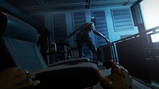Wraith: The Oblivion - Afterlife screenshot: the player crouches behind a cinema seat as a dark, glistening Spectre stalks past in a blue-lit room